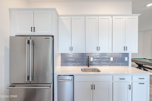 kitchen featuring appliances with stainless steel finishes, sink, tasteful backsplash, and white cabinetry