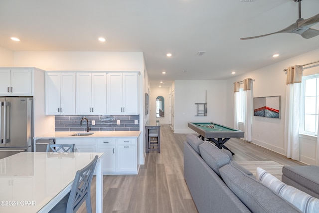 kitchen with sink, pool table, light hardwood / wood-style floors, and tasteful backsplash