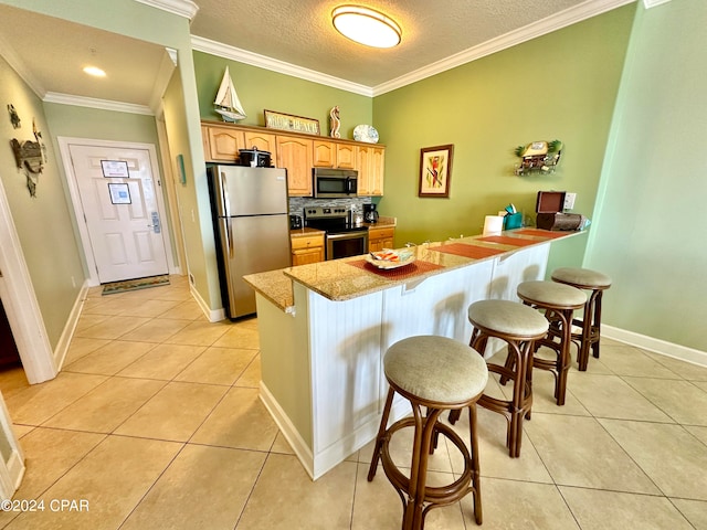 kitchen featuring appliances with stainless steel finishes, light tile floors, tasteful backsplash, a breakfast bar area, and ornamental molding