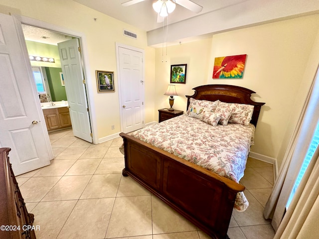 bedroom with ceiling fan, light tile floors, and ensuite bathroom