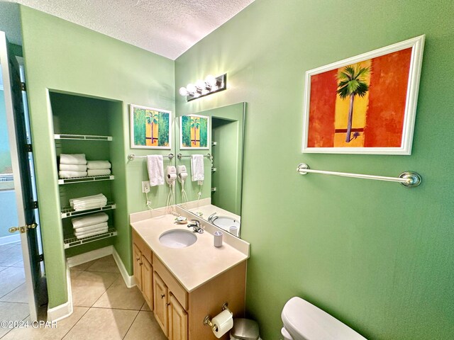 bathroom with vanity with extensive cabinet space, toilet, tile floors, and a textured ceiling