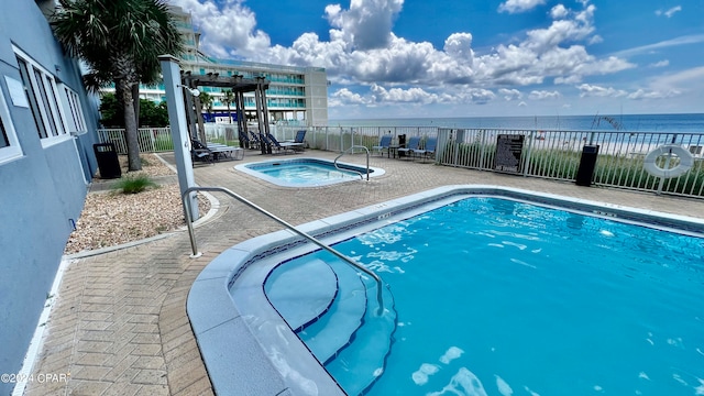 view of swimming pool featuring a hot tub, a patio area, and a water view