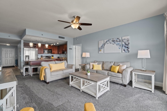 living room featuring rail lighting, visible vents, dark carpet, a ceiling fan, and baseboards