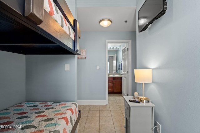 bedroom with baseboards, ensuite bath, and light tile patterned floors