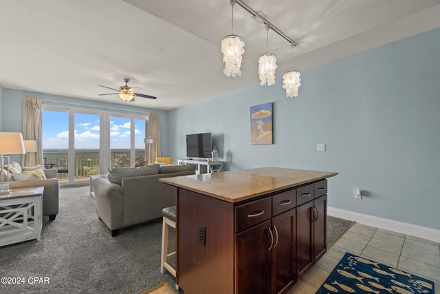 kitchen featuring decorative light fixtures, a breakfast bar area, open floor plan, ceiling fan, and baseboards