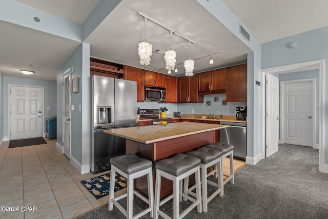 kitchen with a breakfast bar area, stainless steel appliances, a sink, a kitchen island, and visible vents