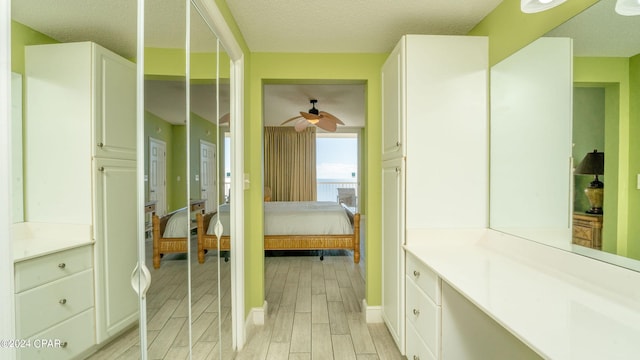 bathroom with hardwood / wood-style flooring, ceiling fan, vanity, and a textured ceiling