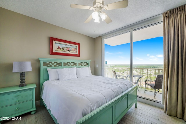 bedroom featuring ceiling fan, hardwood / wood-style flooring, access to outside, and a textured ceiling