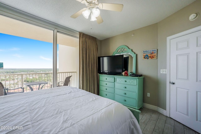 bedroom with ceiling fan, access to exterior, dark hardwood / wood-style floors, and a textured ceiling