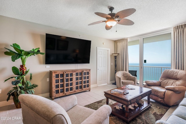 living room featuring light tile flooring, ceiling fan, a water view, and a textured ceiling