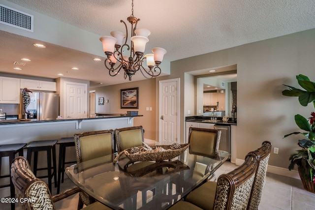 tiled dining area featuring a textured ceiling, sink, and a chandelier