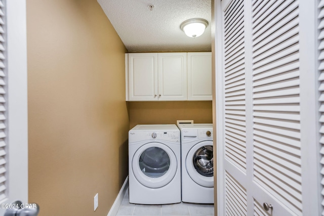 washroom with washing machine and dryer, cabinets, a textured ceiling, washer hookup, and light tile floors