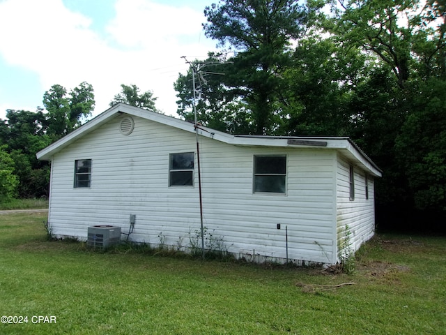 view of side of property with central AC and a yard