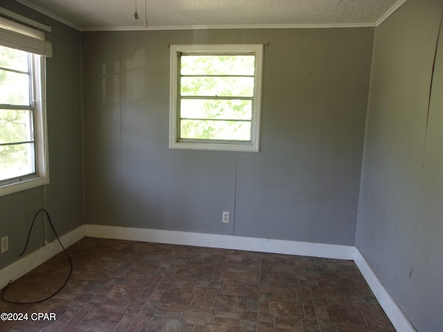 empty room with plenty of natural light, dark tile floors, and a textured ceiling