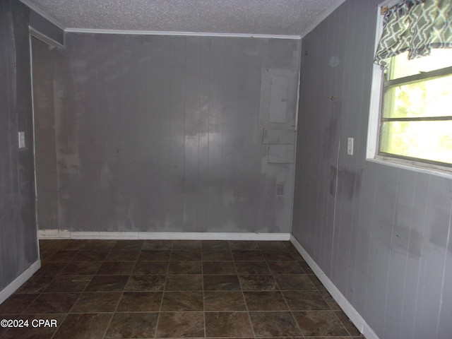 tiled empty room featuring a textured ceiling