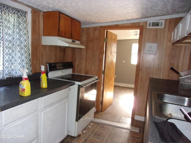 kitchen with exhaust hood, white cabinets, light tile flooring, white range with electric stovetop, and wood walls