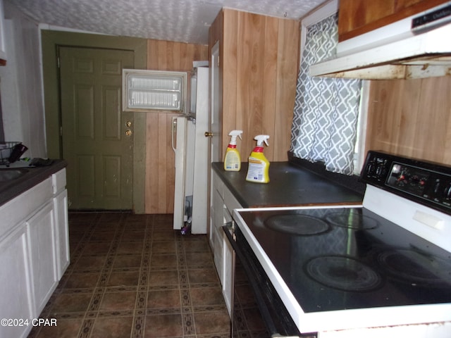 kitchen with dark tile flooring, ventilation hood, range with electric cooktop, and white cabinetry