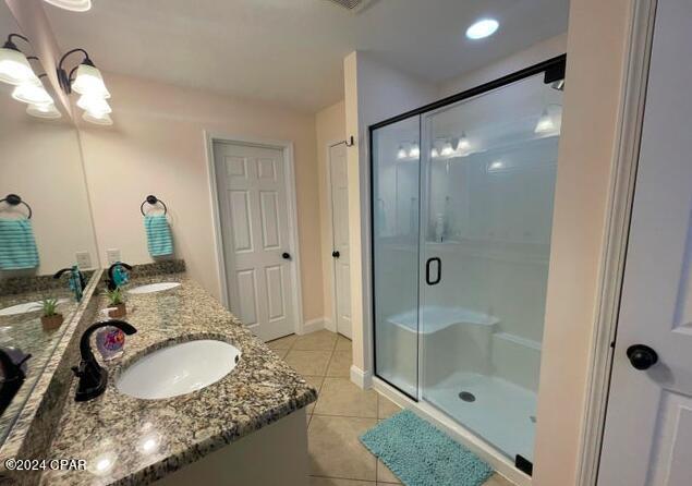 bathroom featuring tile patterned flooring, a shower with door, and vanity