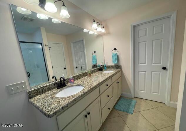 bathroom with a shower with door, vanity, and tile patterned floors