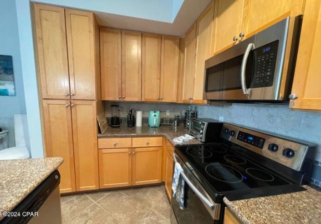 kitchen featuring light stone counters, light tile patterned flooring, decorative backsplash, a skylight, and appliances with stainless steel finishes