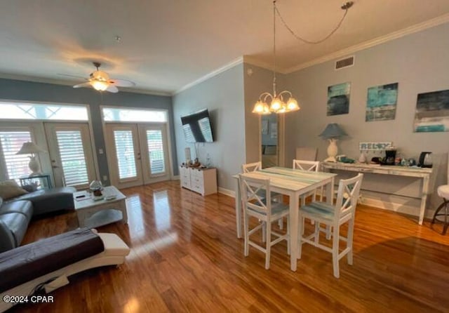 dining room featuring ceiling fan with notable chandelier, french doors, hardwood / wood-style floors, and crown molding