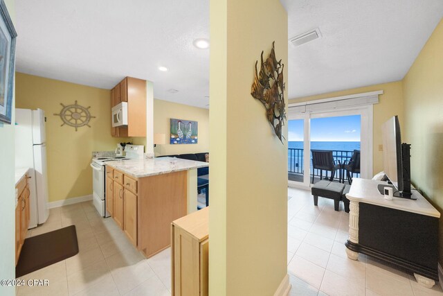 kitchen featuring white appliances, kitchen peninsula, and light tile patterned floors