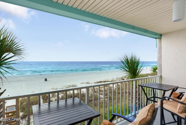 balcony with a water view and a view of the beach