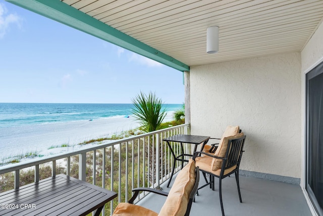 balcony featuring a view of the beach and a water view