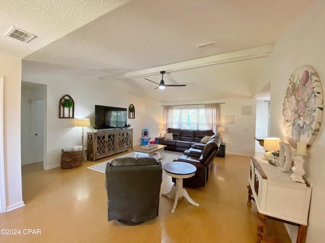 living room featuring vaulted ceiling with beams, ceiling fan, light hardwood / wood-style flooring, and a textured ceiling