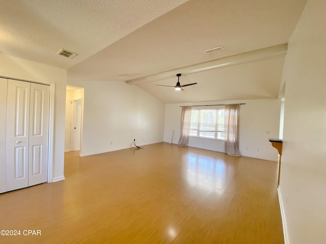 spare room with hardwood / wood-style floors, lofted ceiling with beams, a textured ceiling, and ceiling fan