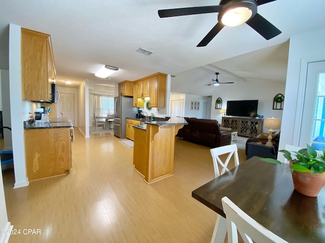 kitchen with kitchen peninsula, a kitchen breakfast bar, stainless steel appliances, vaulted ceiling, and light hardwood / wood-style flooring