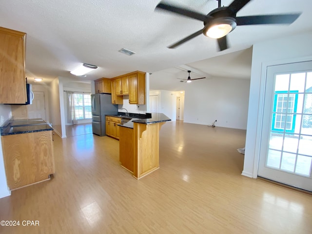 kitchen with stainless steel fridge, a healthy amount of sunlight, kitchen peninsula, and light hardwood / wood-style flooring