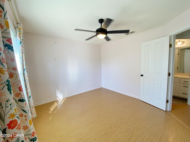 unfurnished bedroom with ceiling fan, light hardwood / wood-style flooring, ensuite bathroom, and a textured ceiling