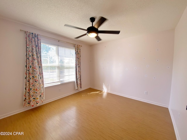 spare room with hardwood / wood-style flooring, ceiling fan, and a textured ceiling