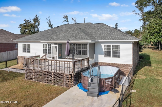 back of house with a lawn, a hot tub, and a deck