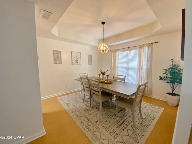 dining area featuring a raised ceiling and light hardwood / wood-style flooring