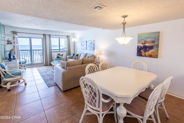 tiled dining room featuring a textured ceiling and a water view