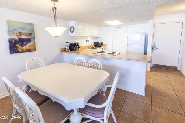 tiled dining area featuring a textured ceiling