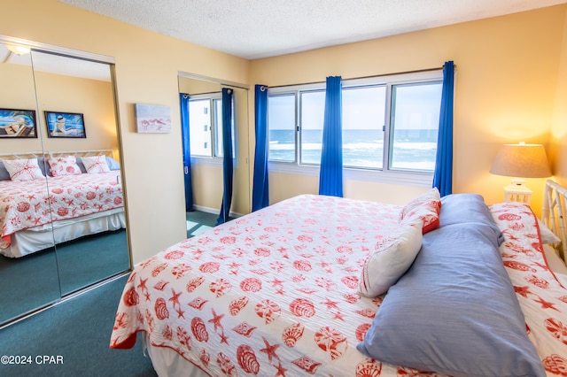 carpeted bedroom with a textured ceiling and a water view