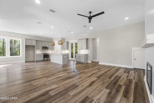 unfurnished living room with hardwood / wood-style flooring, a wealth of natural light, ceiling fan, and sink