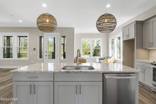 kitchen featuring appliances with stainless steel finishes, plenty of natural light, sink, and light stone counters