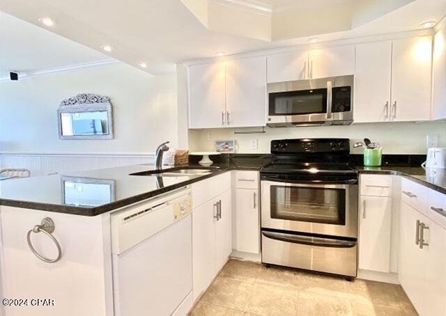 kitchen featuring appliances with stainless steel finishes, light tile floors, white cabinets, sink, and kitchen peninsula