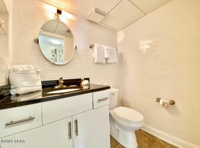 bathroom featuring tile walls, toilet, tile flooring, and vanity