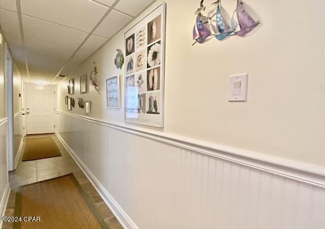 hall featuring tile flooring and a paneled ceiling