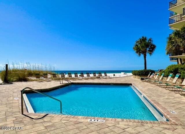 view of swimming pool with a water view and a patio area