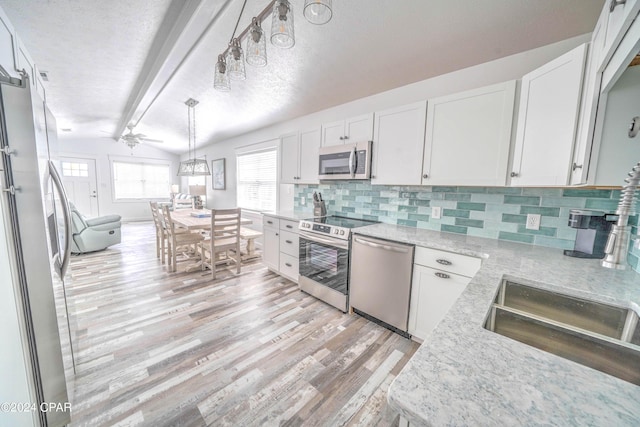 kitchen with backsplash, white cabinetry, appliances with stainless steel finishes, and lofted ceiling with beams