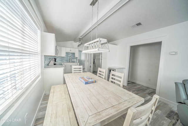 dining room with light hardwood / wood-style floors, sink, a wealth of natural light, and vaulted ceiling