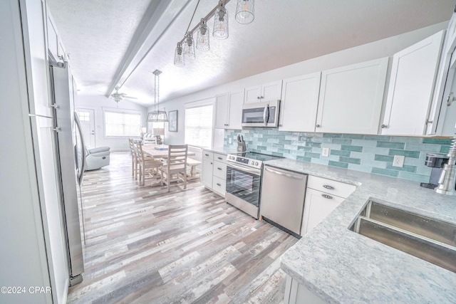 kitchen featuring vaulted ceiling with beams, appliances with stainless steel finishes, and white cabinets