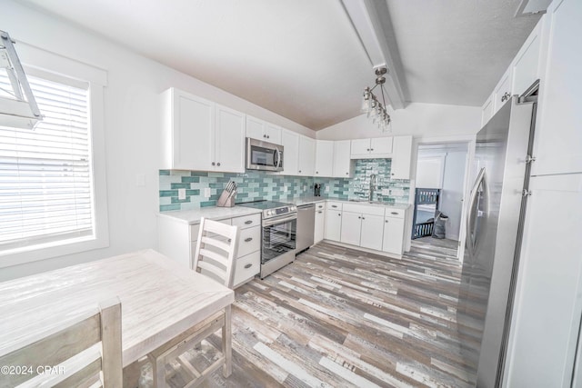 kitchen with white cabinetry, appliances with stainless steel finishes, lofted ceiling with beams, and tasteful backsplash