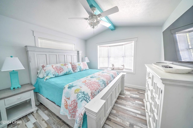 bedroom with ceiling fan, lofted ceiling with beams, multiple windows, and light hardwood / wood-style flooring